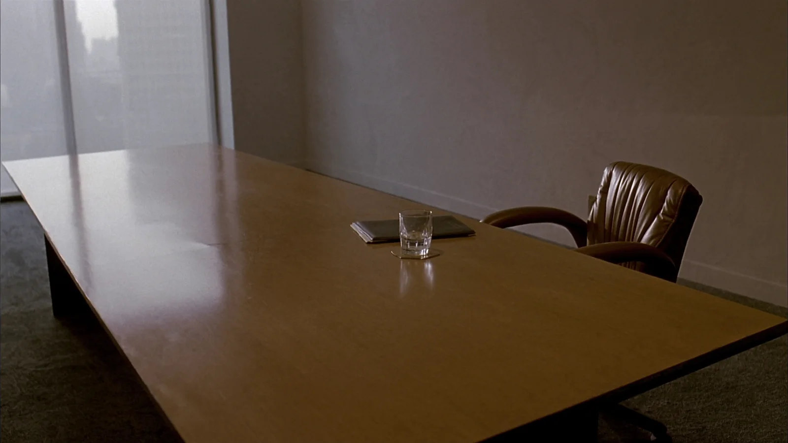 An empty law office conference room with one chair pulled out and morning light through a window