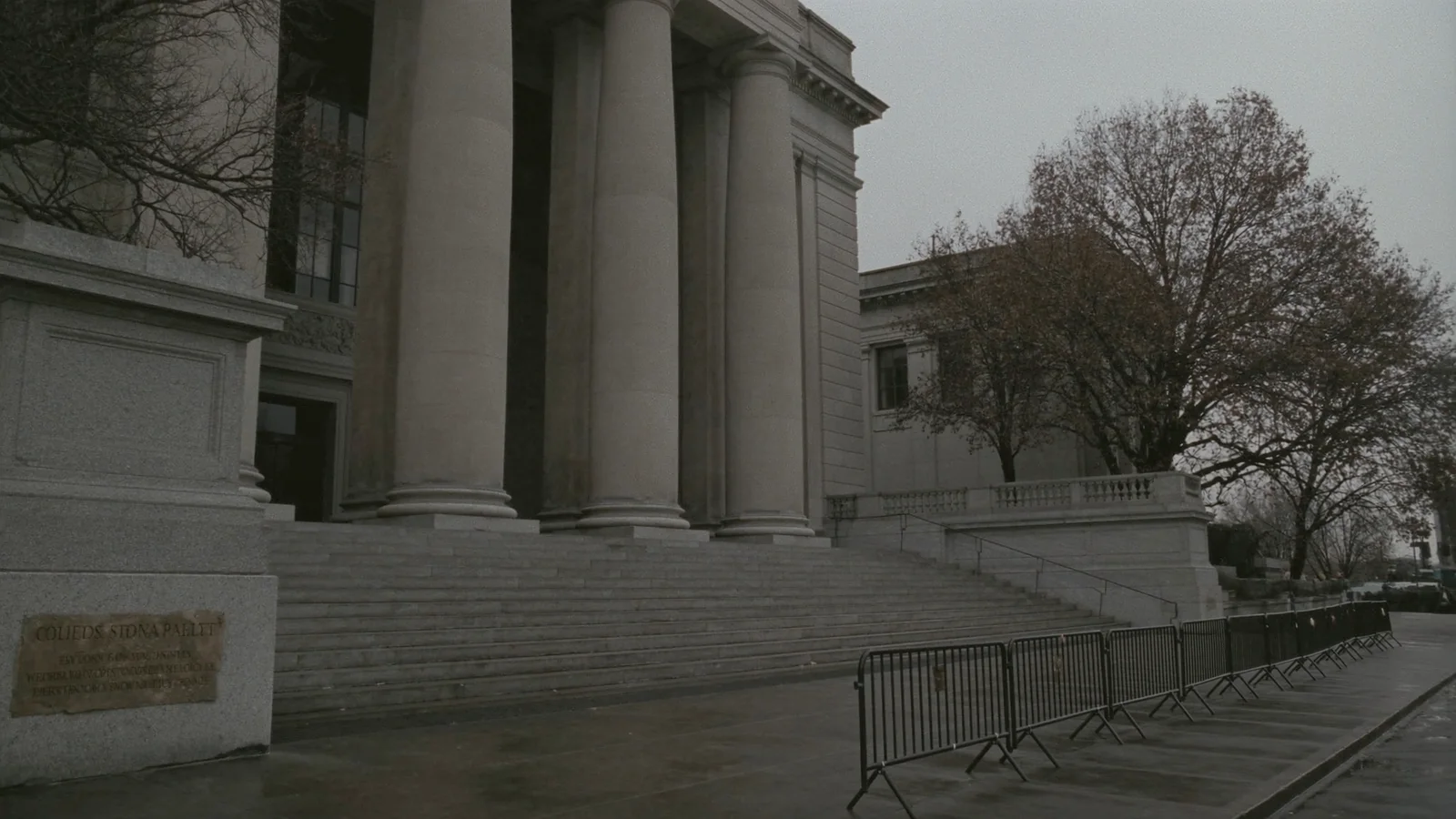 The wide empty stone steps of a courthouse with press barriers set along one side