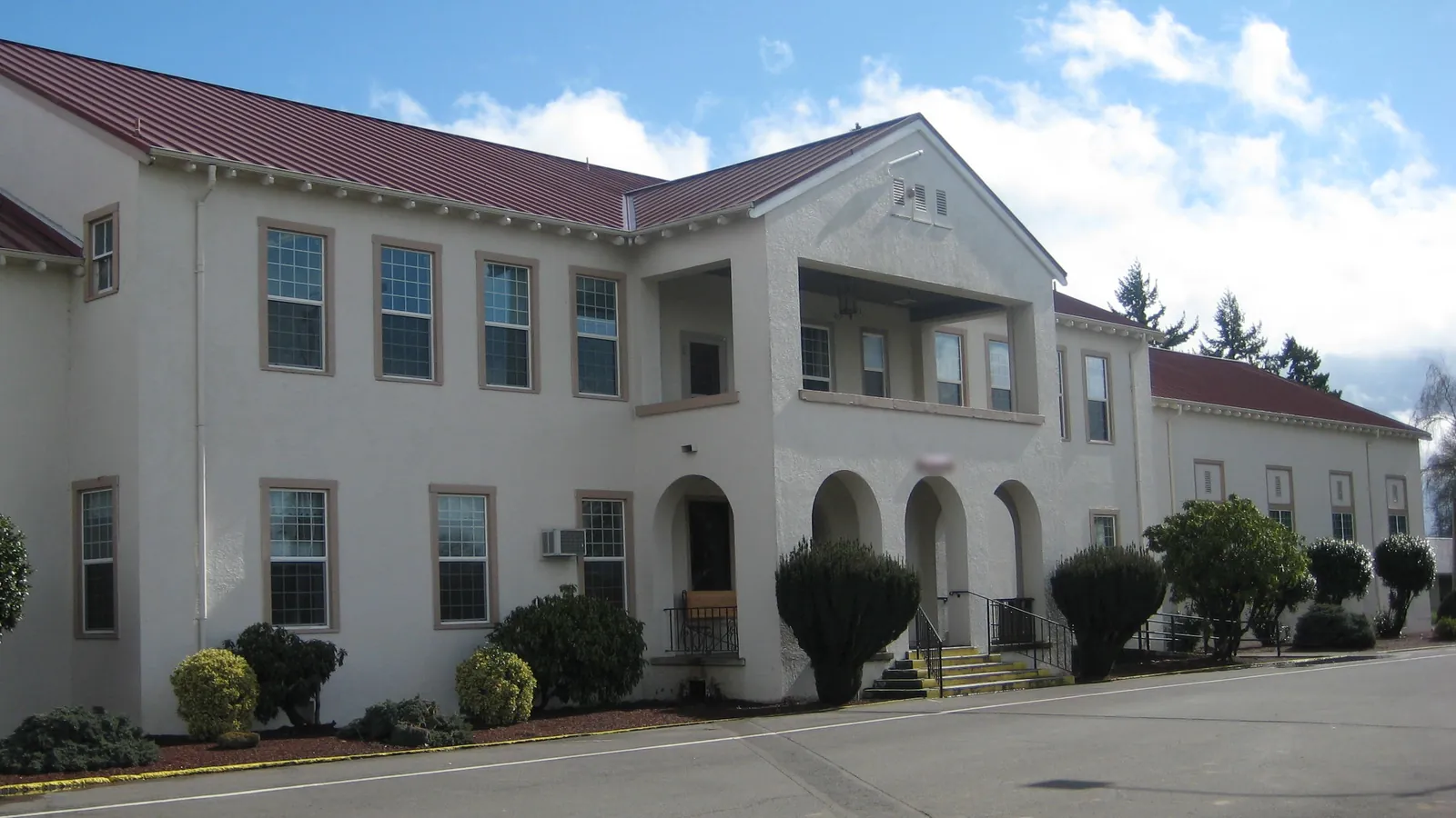 The two-story white stucco administration building at MacLaren Youth Correctional Facility in Woodburn, with arched entrances and a red metal roof
