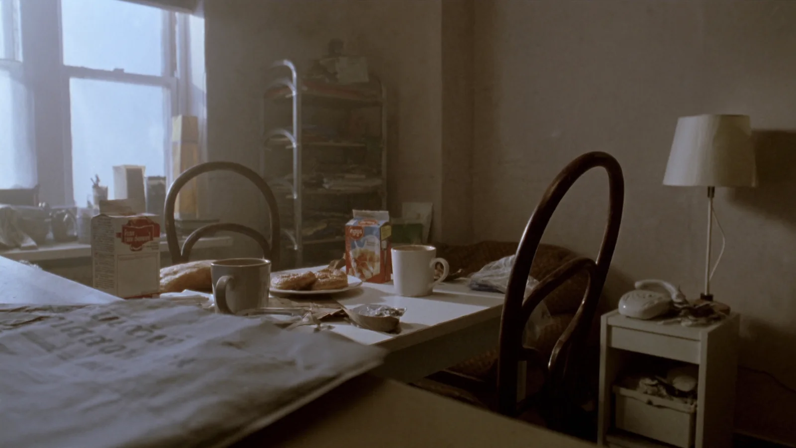 Two mugs of coffee on a kitchen table at dawn with one chair pushed back
